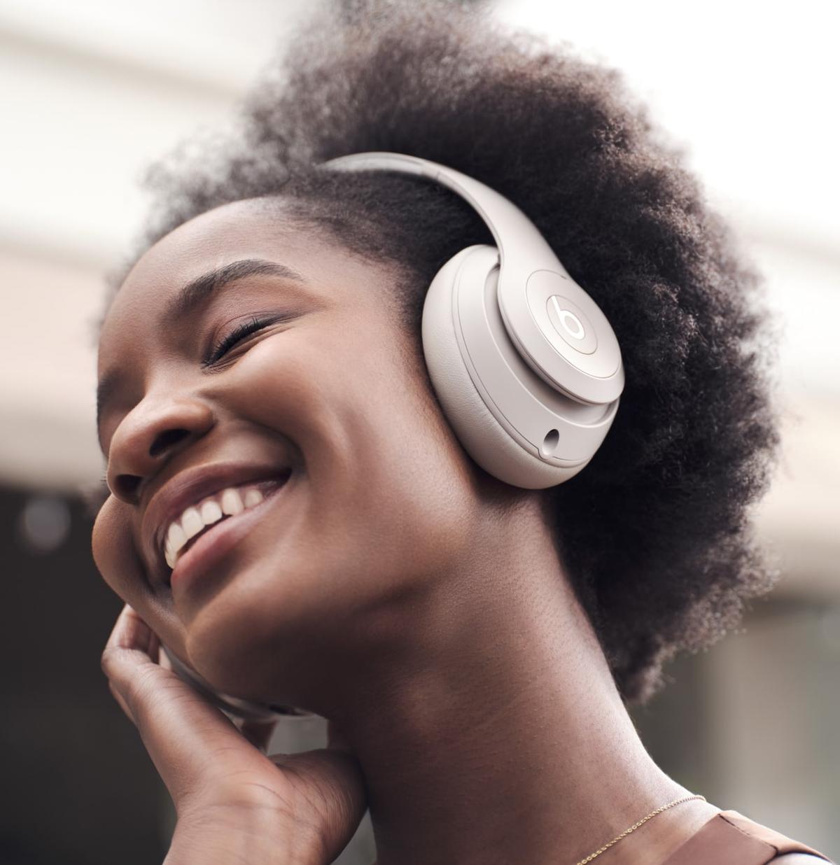 Woman wearing Beats Studio Pro smiling outdoors — transparency mode lifestyle